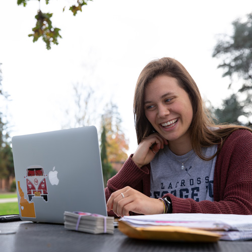 Student sitting in the campus quad with a laptop