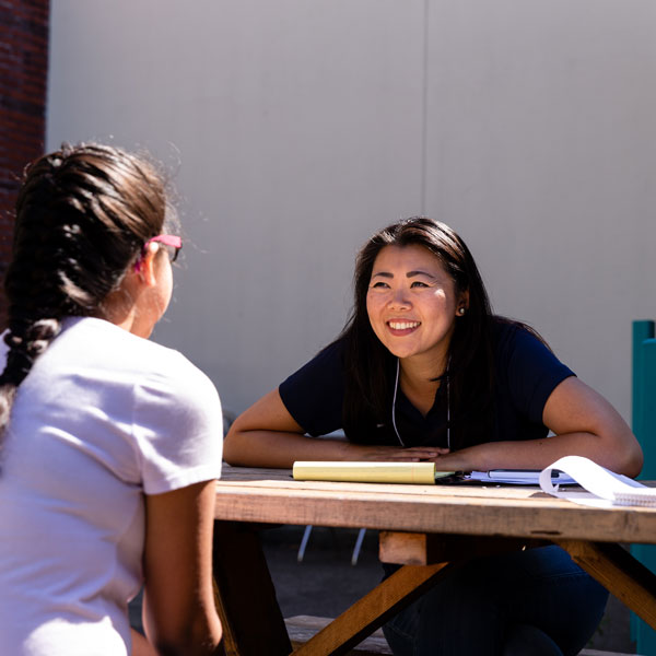student teacher talks outside with young student