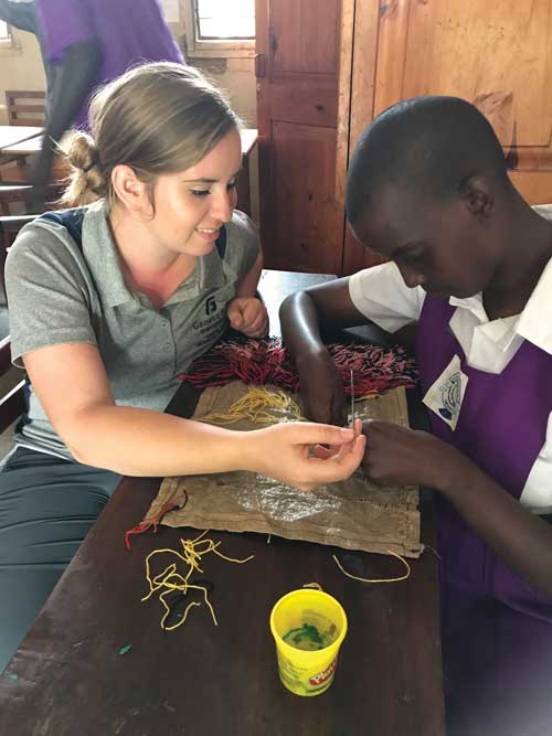 Student and a child work on beadwork