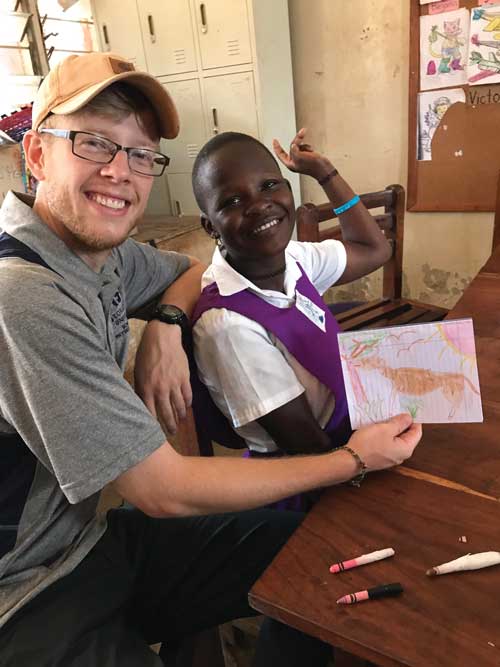 Caleb Zimmerman draws with one of the Ugandan students
