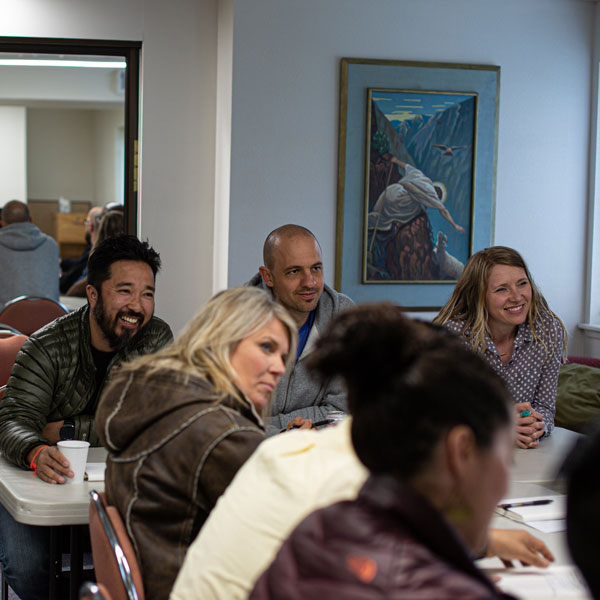 3 seminary students in a class sit at a table