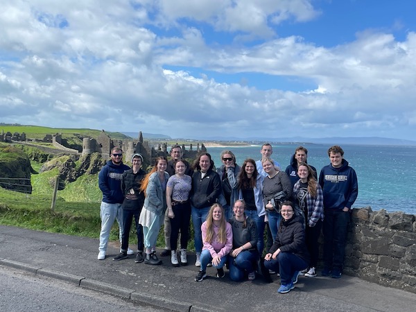 Students stand with a view of the ocean behind them