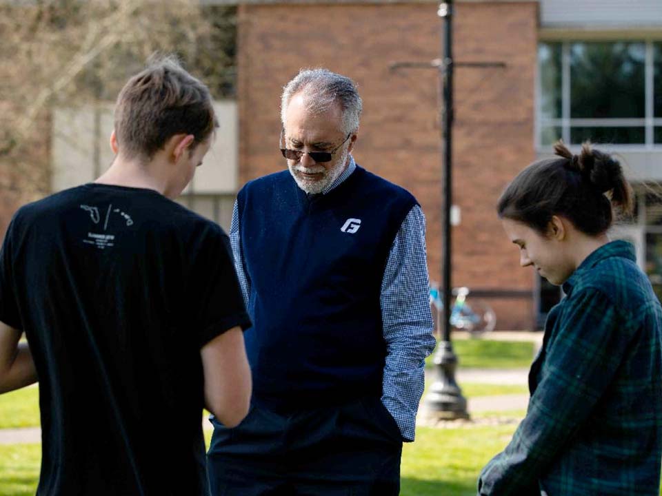 Robin Baker praying with students