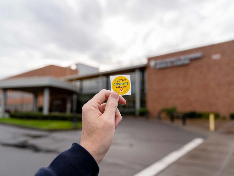 Hand holding sticker reading 'I got my COVID vaccine'