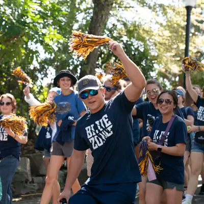 A male student cheers as fans parade behind him
