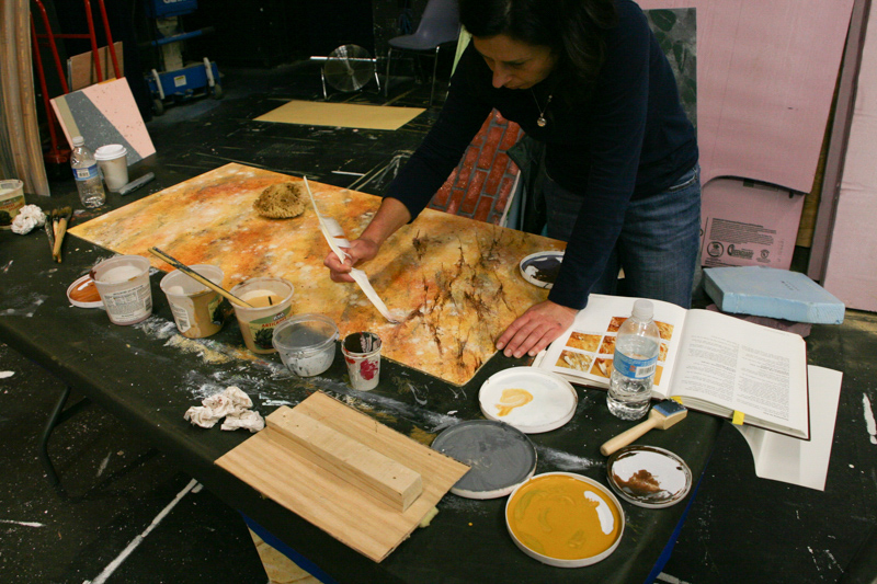 A woman paints scenic art