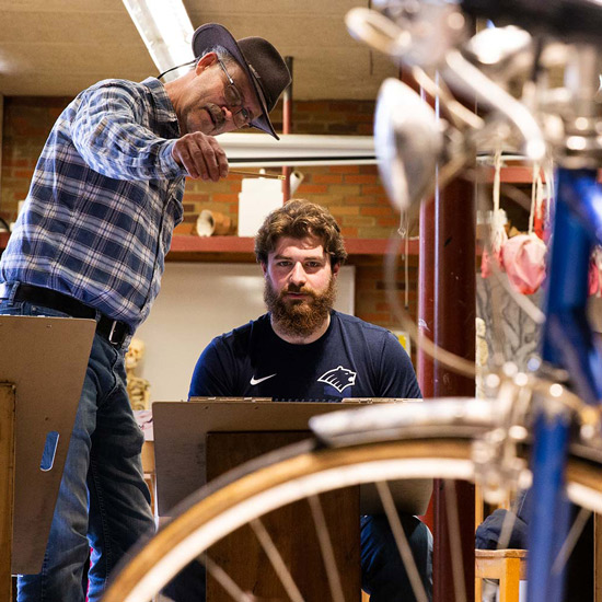 Drawing professor shows student how to draw bicycle