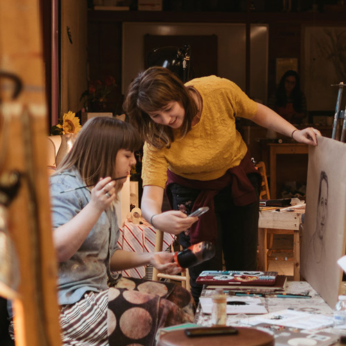 A student shows another student her phone in painting class