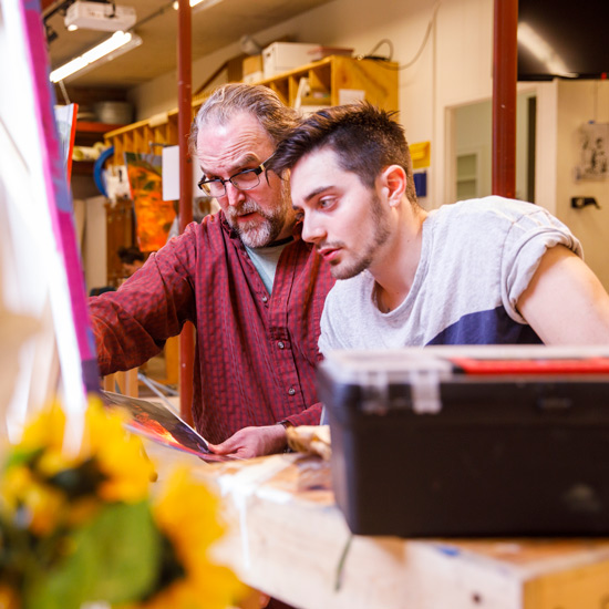 Professor Tim Timmerman works with a student on a painting