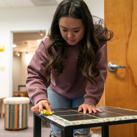 Student cleans tile on a table
