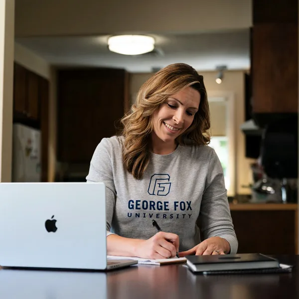 A 90-degree online student works on her laptop at home