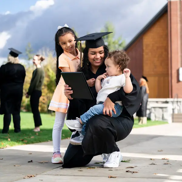 Associates graduate hugs her two kids for a photo