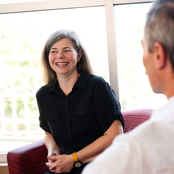 A George Fox graduate speaks with a colleague in a meeting  