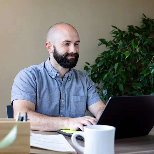 A George Fox online management student smiles and work in his office