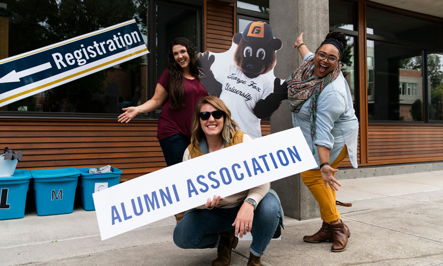 Students hold an "alumni association" sign