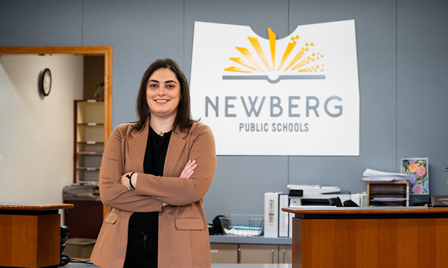 Brittney Morales standing in front of a sign for a school