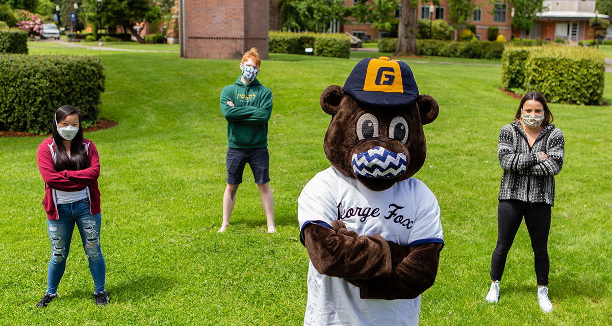 Students and mascot Pennington bear standing on the campus quad wearing masks
