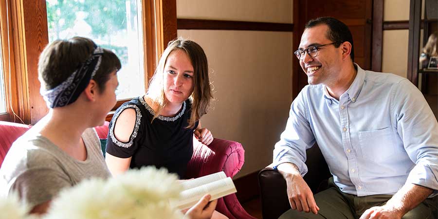 A smiling professor speaks with two students