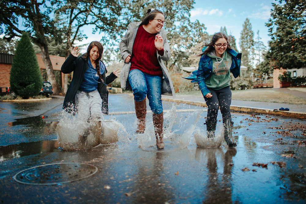 Three students jump in a big puddle
