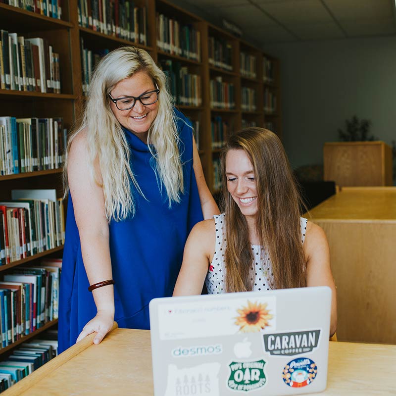 A professor smiles while helping a student