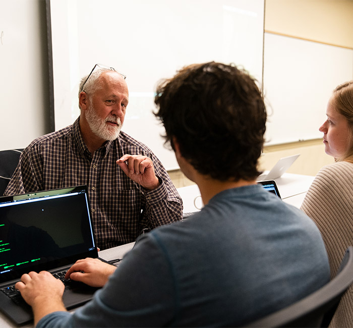 A professor speaks with two students