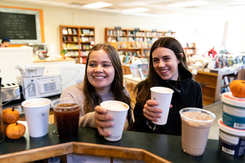 Two girls get warm drinks at a coffee shop