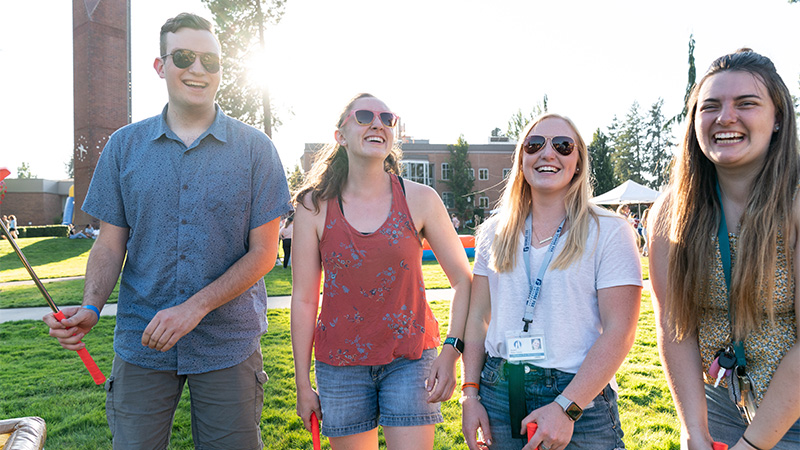 Four friends laugh on the quad