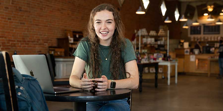 A girl with a mug of coffee smiles