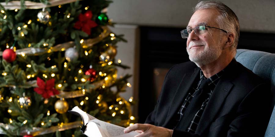 President Baker Reading next to a Christmas tree