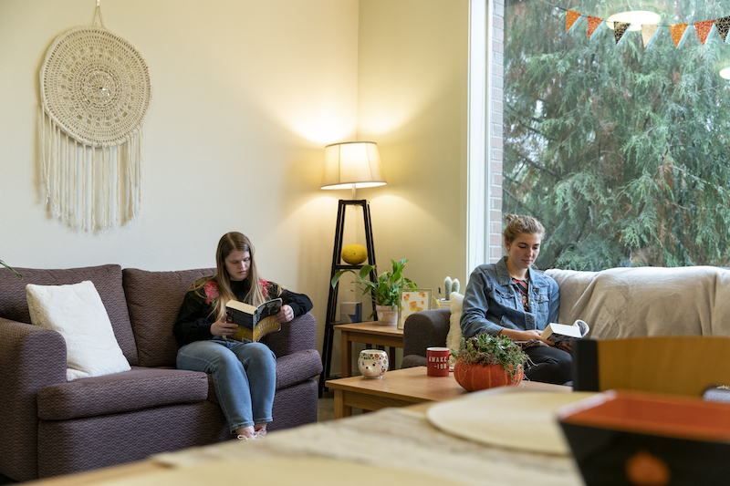 Two girls read in their apartment