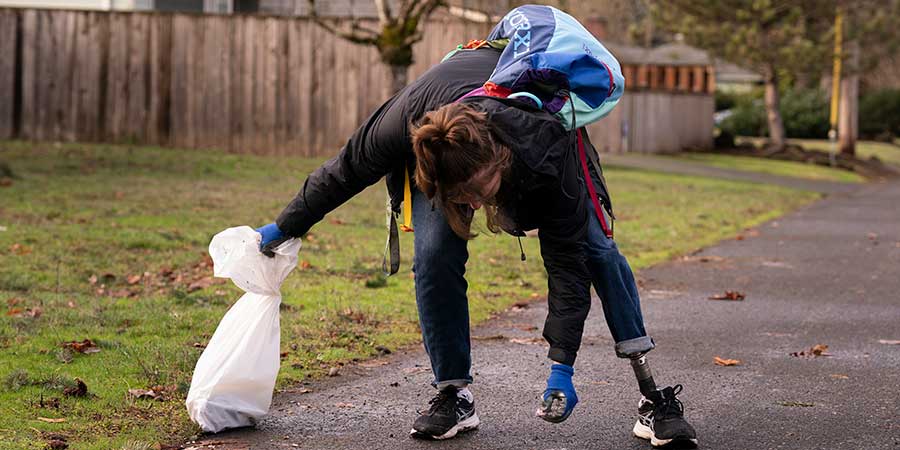 student picking up trash on side of road