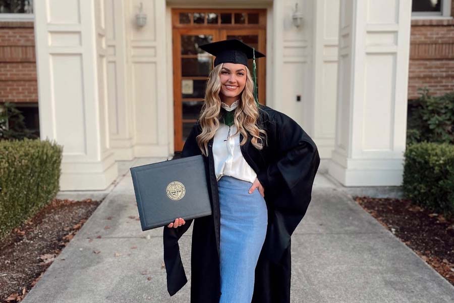 Lance in graduation gown with her diploma