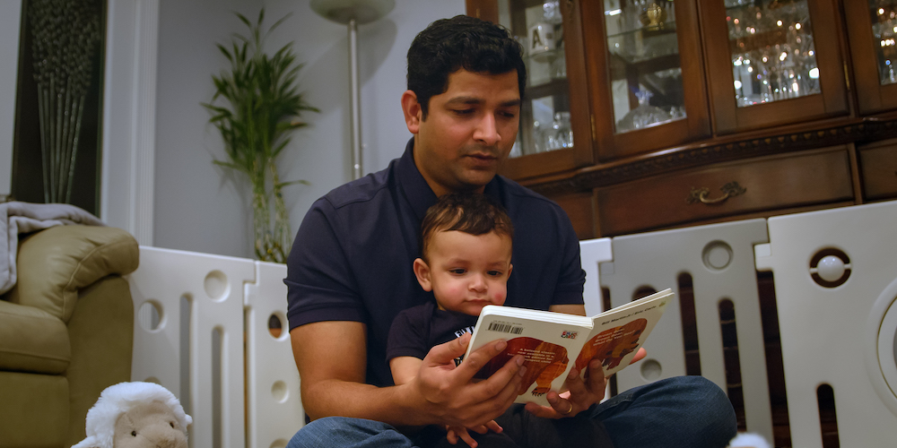 Suhail reads a book to his son.