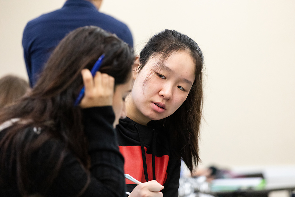 Two students taking notes one looking at the camera