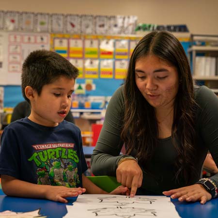 A teacher pointing to something on a paper