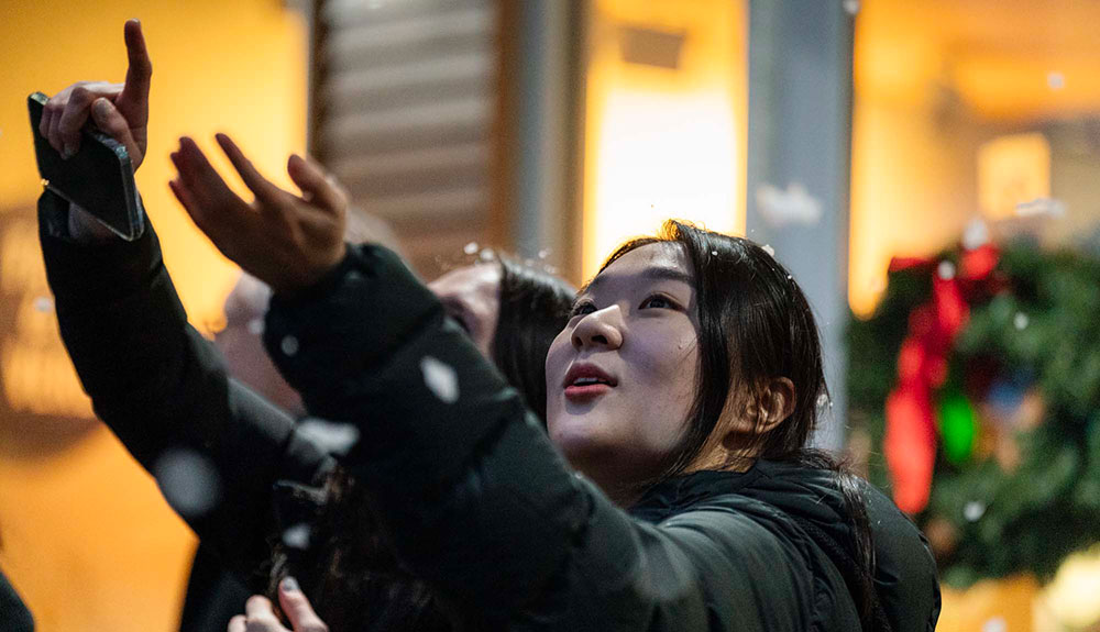 two students reaching towards snowflakes