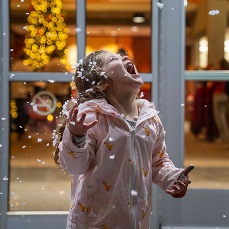child looking up at snowflakes