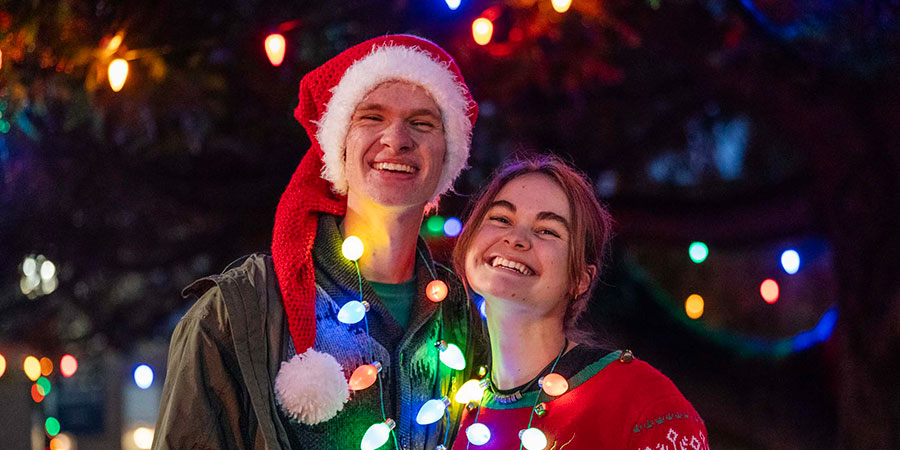 two students posing under Christmas lights