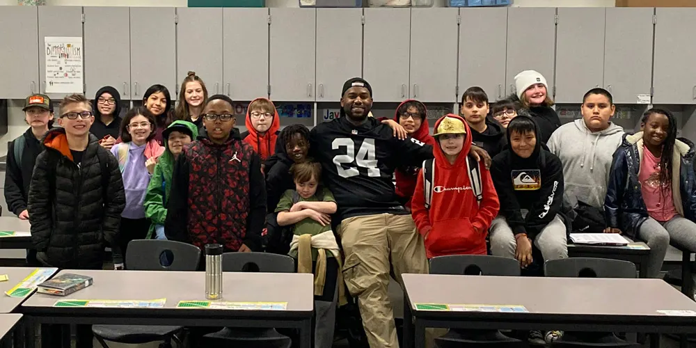 Jason and his students in his classroom pose for a photo