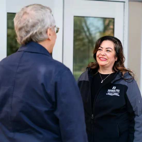 Grace Witt talks with a colleague in front of a building on campus.