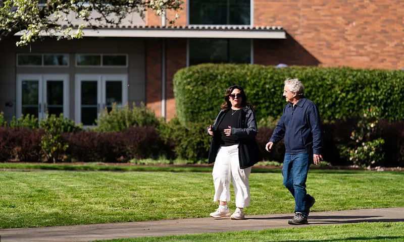 Grace walks around George Fox's campus with a colleague