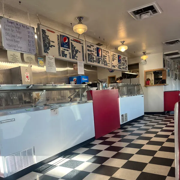 The inside of Jem100, a black and white tile floor with vintage menu signs