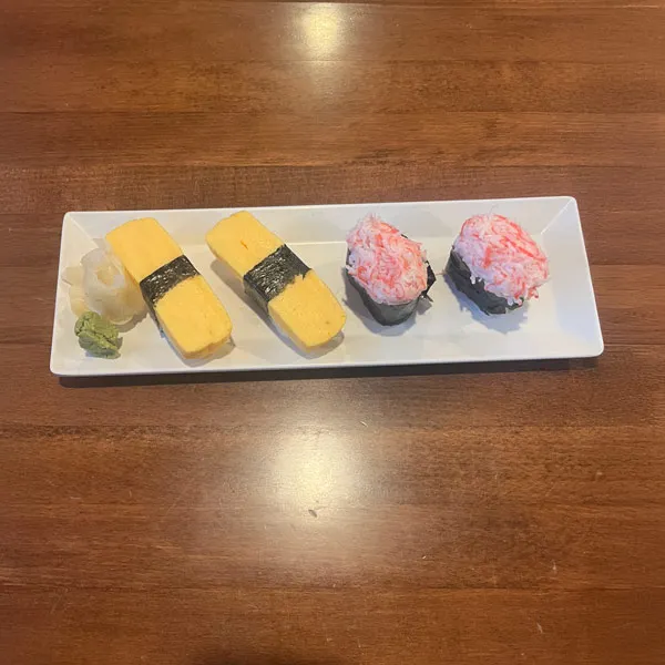 Two pairs of sushi plated on a wooden table