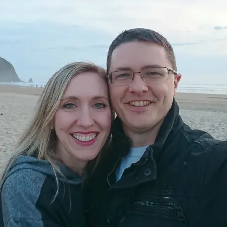 Hayley and Jon Cummings smiling at the windy beach together