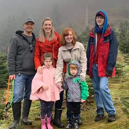 Hayley and her family smiling standing in the rain at a Christmas tree farm