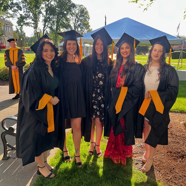 Rachel standing with a cluster of friends smiling at graduation
