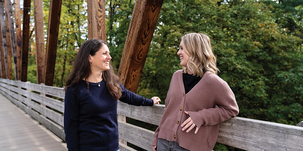 A mentor and mentee talking on a bridge