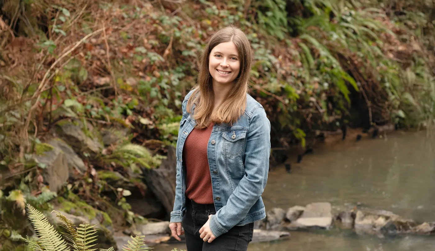 OT student Elizabeth Schroeder poses for a photo outside by the creek on campus