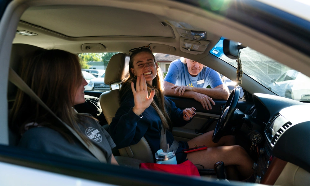 student in their car waving after arriving to campus