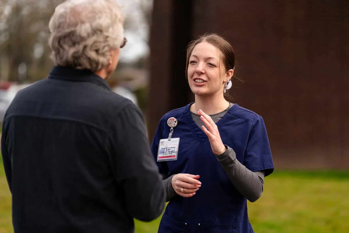 Clark speaks with an older individual outside the hospital